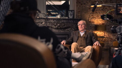 La personne interviewé est assise dans un fauteil, le journaliste en face de lui et la présence du micro dans le cadre d'un documentaire de Licence 3.