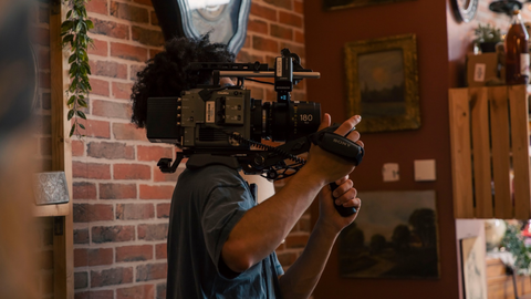 Un jeune homme porte une caméra sur le tournage d'un film.